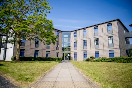Cavendish Hall - a cream coloured building with large windows. There is a path through grass leading to the entrance.