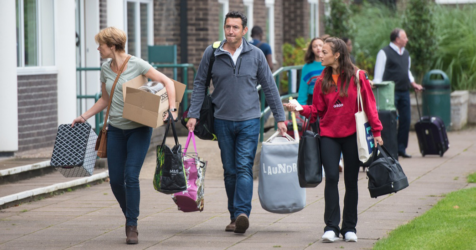 A student and her parents carrying boxes and bags of personal belongings to move into student accommodation