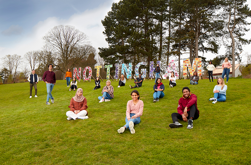 Students sat by the Nottingham sign on campus