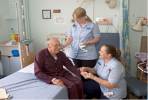 Nurses attending a patient in a hospital bed