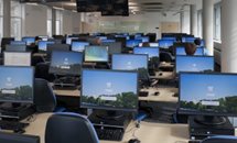 row of desks with PC screens turned on