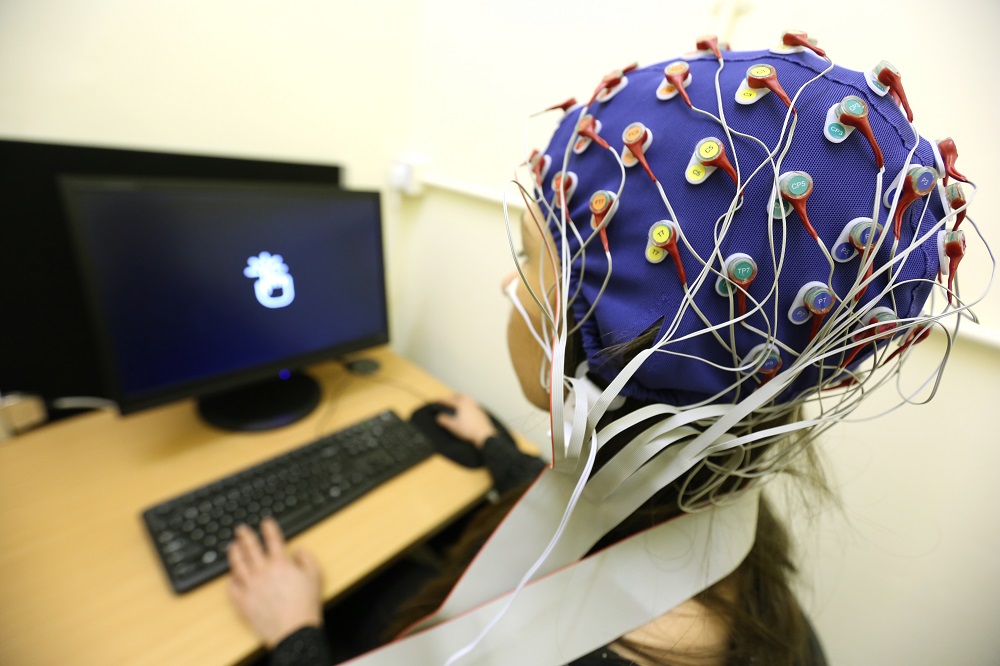 Person wearing skullcap covered with electrodes performing computer test