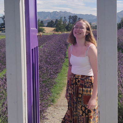 Emily LeHegarat smiling inside a pretend doorway in a lavender field