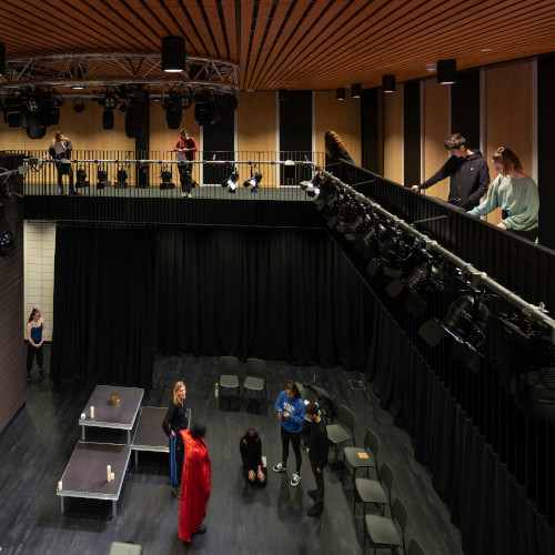 Students rehearsing in Monica Partridge performance space while other's look down from balcony
