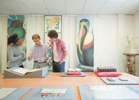 Two students and a tutor discuss artwork in a gallery