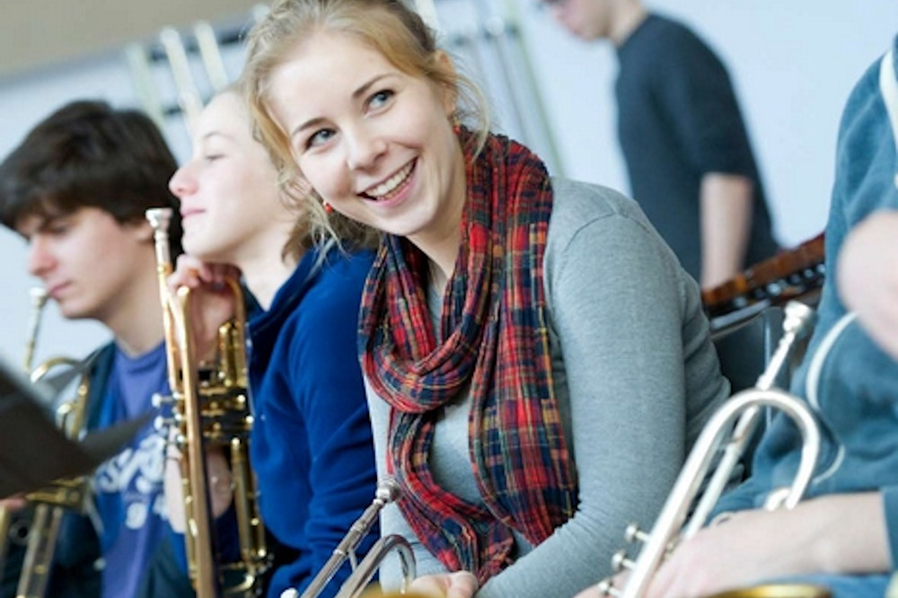 Trumpet player taking a beak and smiling at bandmates
