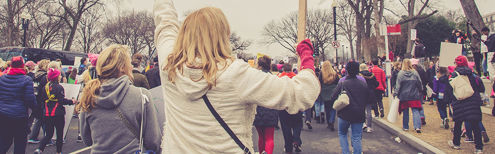 A protest march with a sign reading 'we can do better'