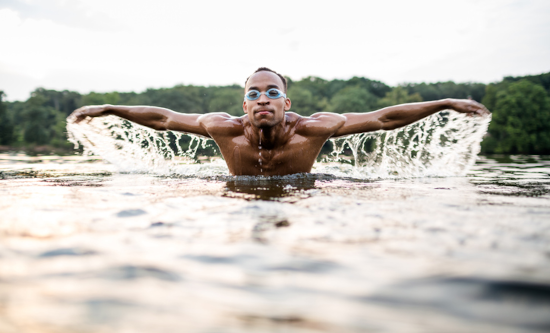 Head on view of man swimming in lake doing butterfly stroke