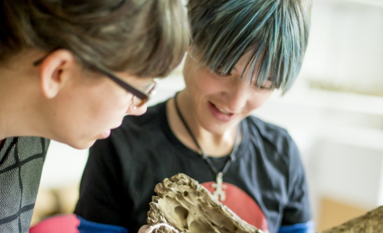 Close up of two people examining a large bone