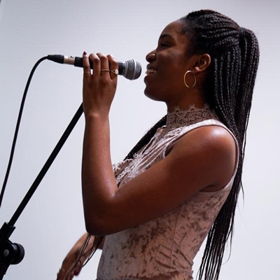 Tamaratare Amgbaduba singing into a microphone and smiling