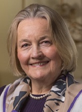 Head and shoulders photo of Dame Mary Marsh. Mary has blond chin length hair and is wearing a beaded necklace and dark top. Mary also has a scarf around her shoulders.