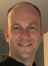 Head and shoulders photo of Hugh Jacques. Hugh is smiling and wearing a dark shirt.