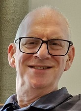 head and shoulders photo of Richard Oblath. Richard is smiling and he is wearing glasses and a grey shirt.