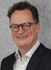 Head and shoulders photo of Keith Burgess. Keith has dark hair and is wearing glasses, a dark jacket and a checked shirt.