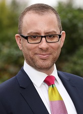 Head and shoulders photo of Steve Lofthouse. Steve is wearing glasses, a dark jacket with a white shirt and a red, yellow and purple tie.