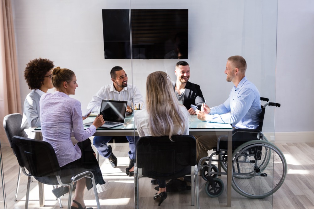 A male in wheelchair in office with colleagues