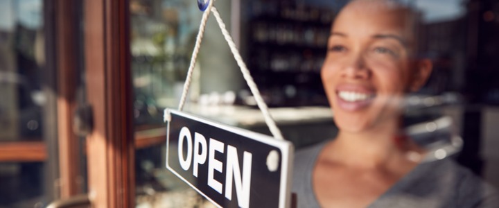 Female owner of coffee shop turning round open sign