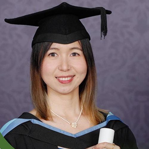 Xiaoli Fu (Sherry) smiling, short brown highlighted hair, wearing a black graduation hat and gown with blue trim in front of a dark swirly grey background.