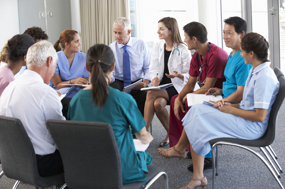 A group of various medical professionals sat in a circle having a meeting.