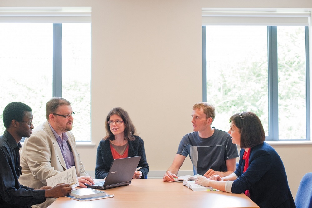 A group of people sat around a table having a meeting