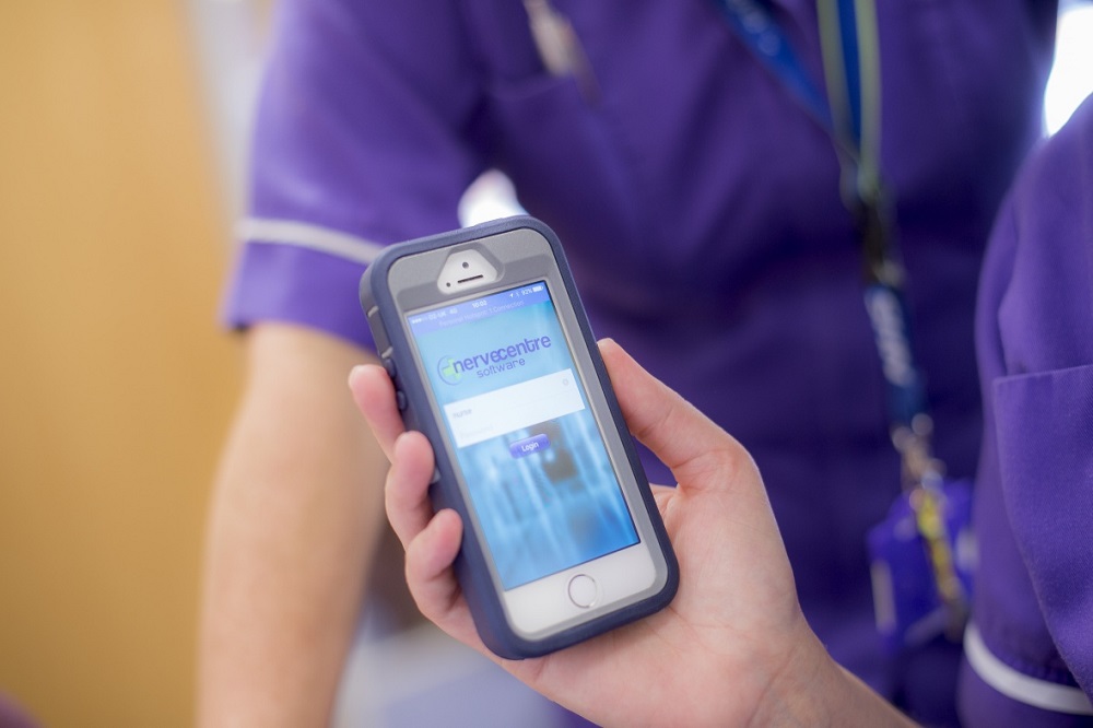 Nurse in blue uniform holding hand held devise for monitoring healthcare