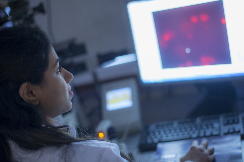 A clinician studying an data on a computer screen in a lab setting.