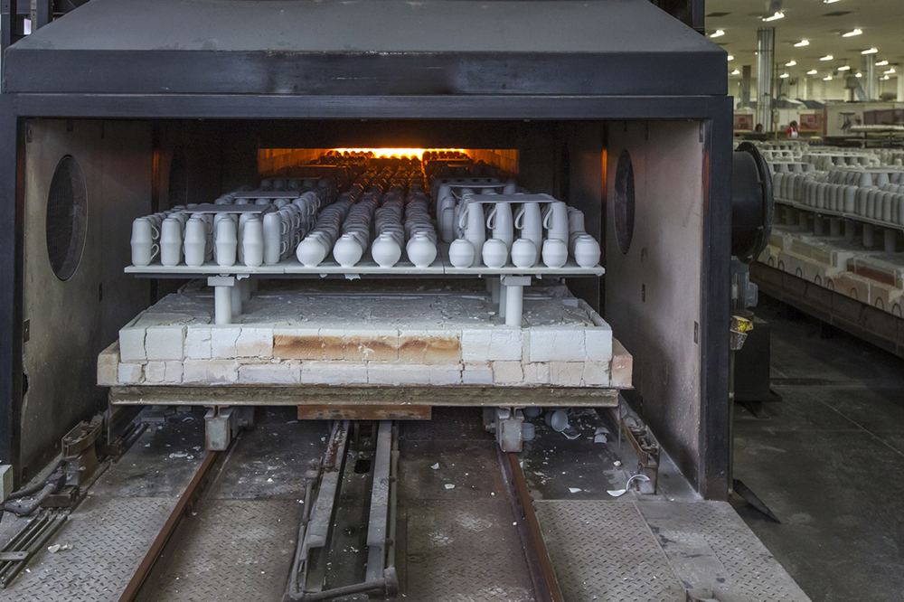 Ceramics workshop with large scale kiln with ceramics inside it. Other kiln dried ceramics are visible in the background.