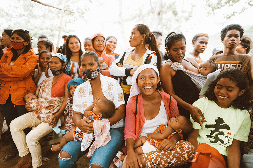 A group photo of women and girls from the Ata Manobo indigenous community in a village on the island of Mindanao - Philippines. Some women are holding their babies. Many are smiling.