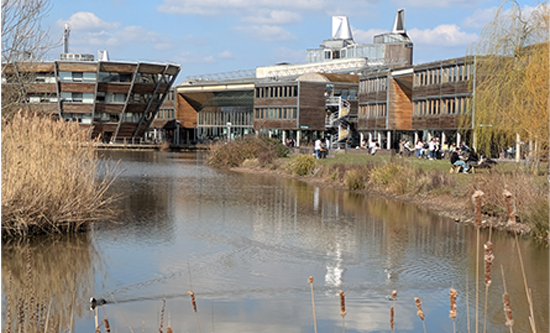 View of Jubilee Campus with lake and wooden buildings winding around path and large library