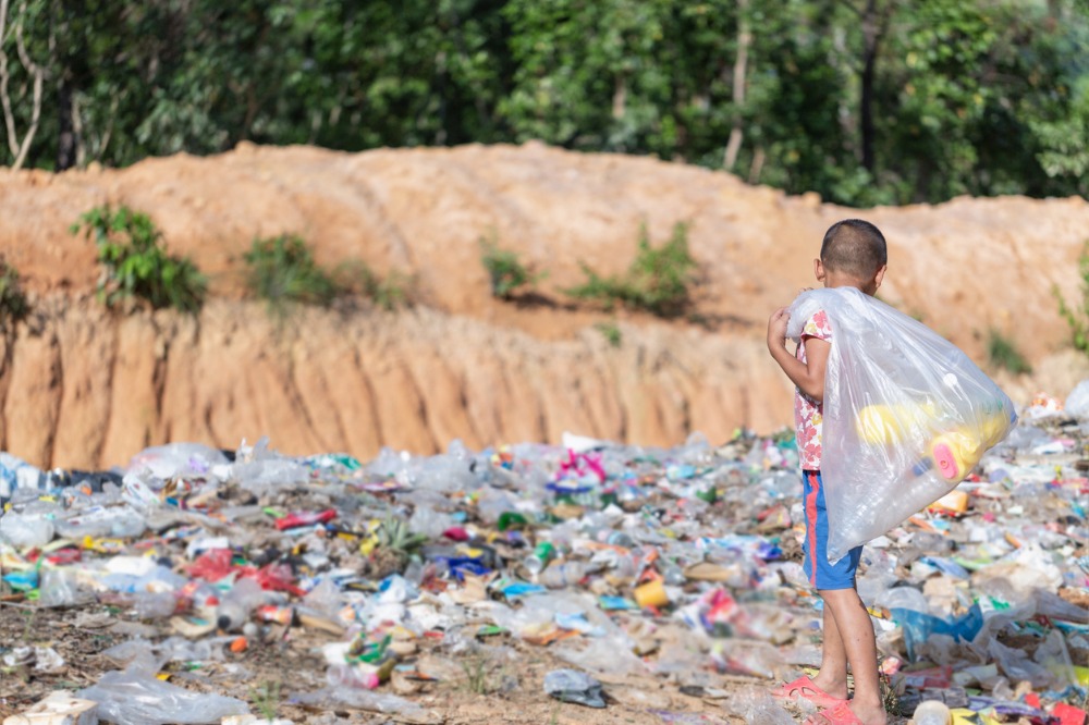 A poor boy collecting garbage waste from a landfill