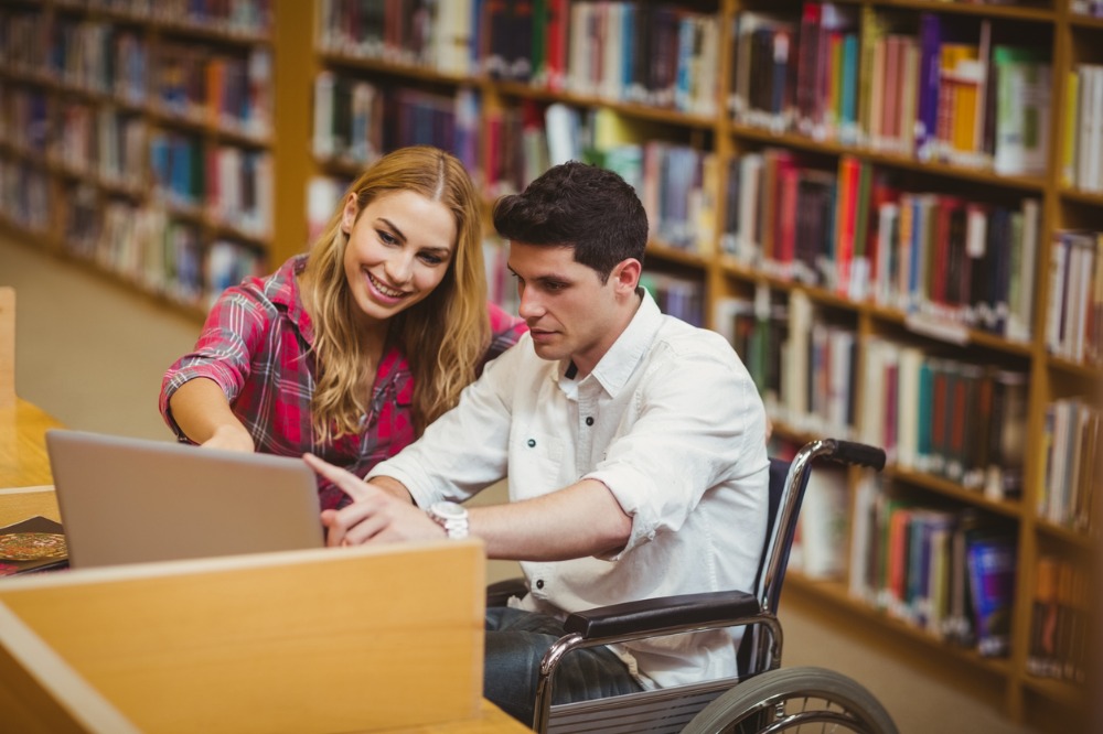 A student in a wheelchair working with a classmate in the library