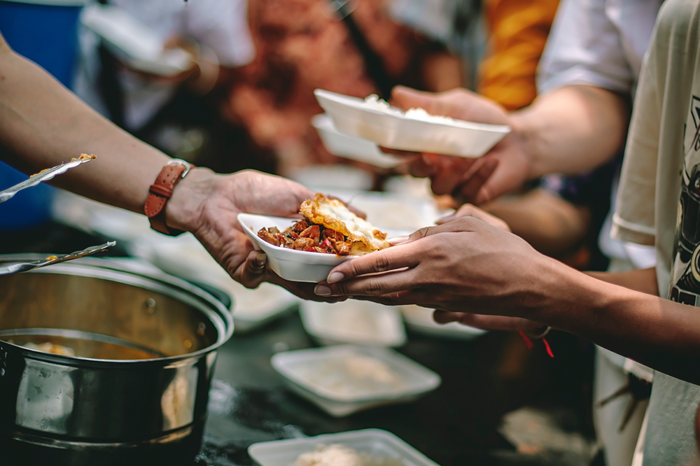 Image of food being handed out in a community food kitchen for people in poverty.