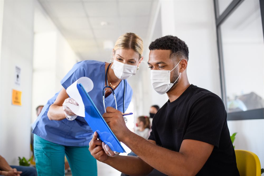 A medical person talking to a patient who is signing paperwork.