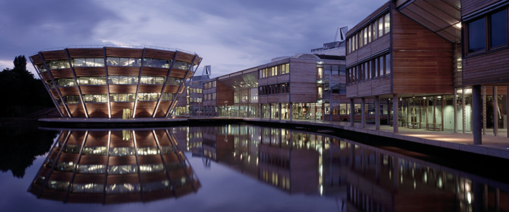 The Learning Resource Centre, lake and buildings on Jubilee Campus, at dusk, with the building's reflection in the lake.