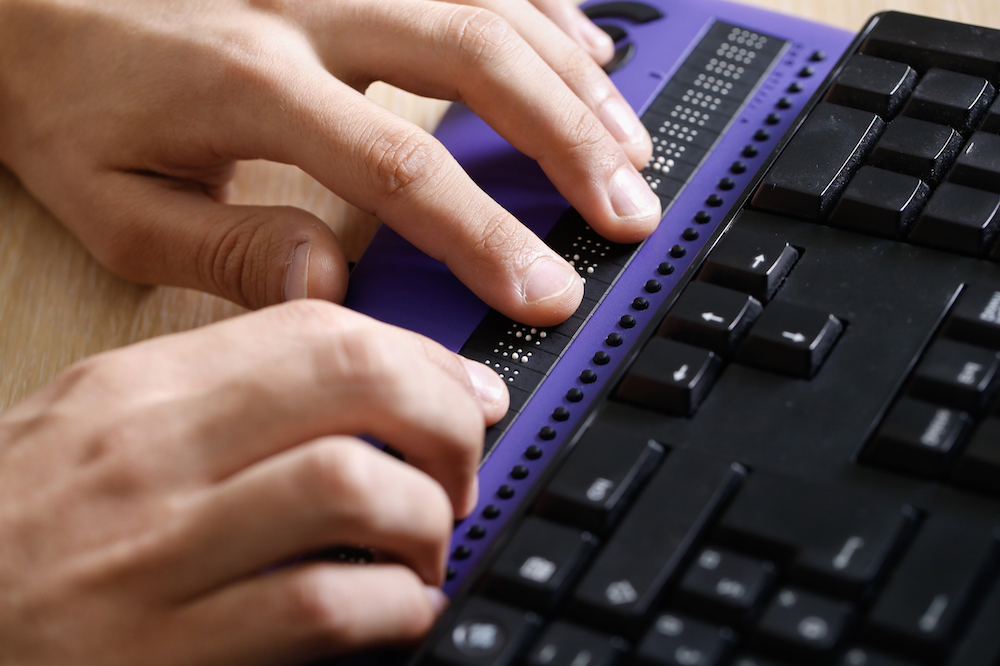 Close up image of someone using a Braille keyboard