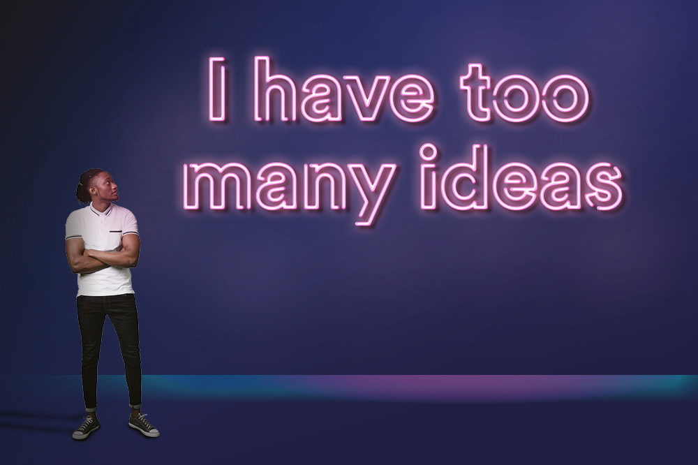 Man looking at a neon sign saying 'I have too many ideas'