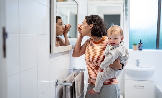 Mother holding her baby while getting ready in the mirror