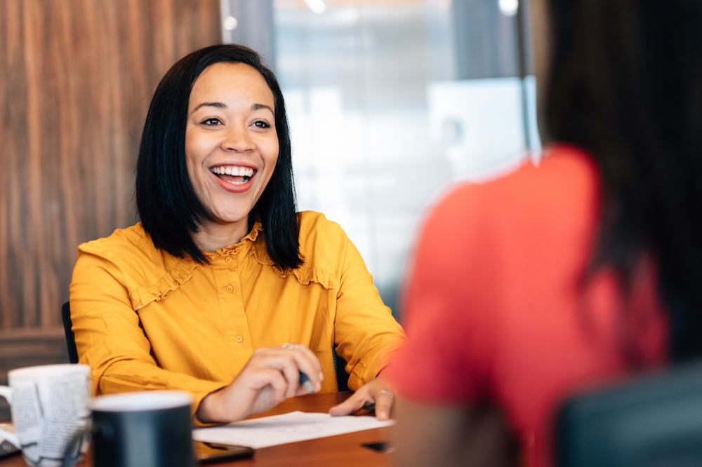 Woman smiling sat at a desk with an applicant