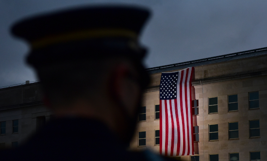 A soldier standing in front of the American flag unfurled outside the Pentagon at dawn
