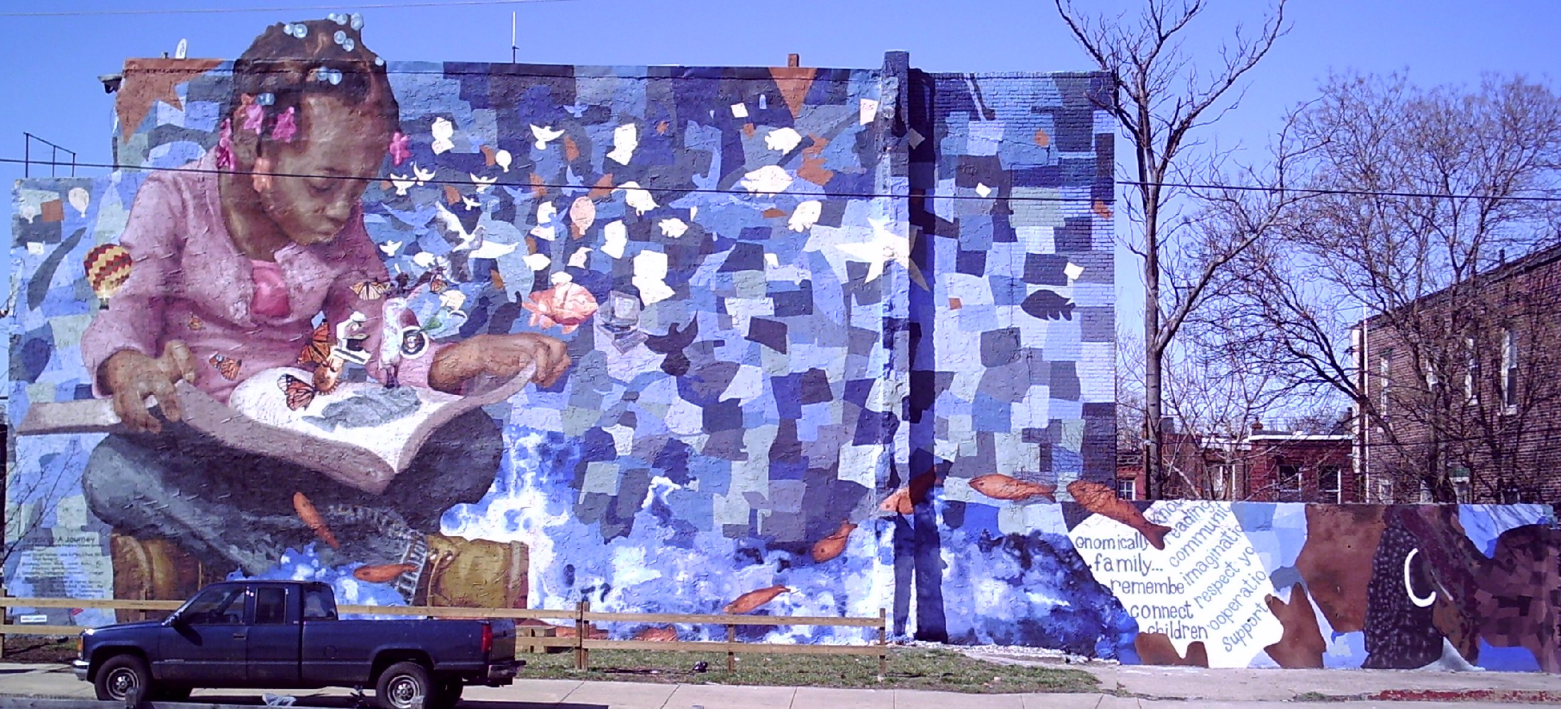 A mural painted onto a wall of a little girl reading a book