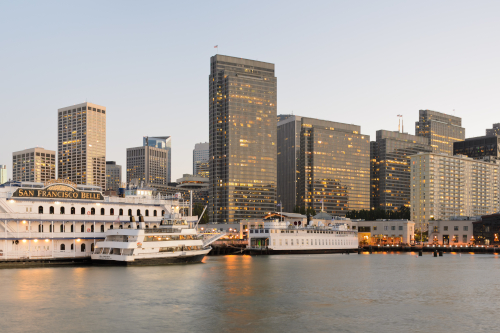 Two-segment panorama of San Francisco from Pier 7 at dusk. In the foreground one can see ships docked at Pier 3, with Financial District skyscrapers in the background. At the left is the Bay Bridge. CC BY-SA 3.0 by King of Hearts on Wikimedia.