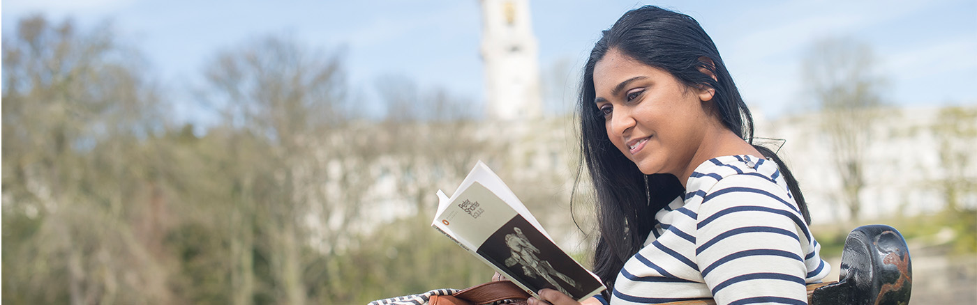 Woman absorbed in reading a book outdoors at the University