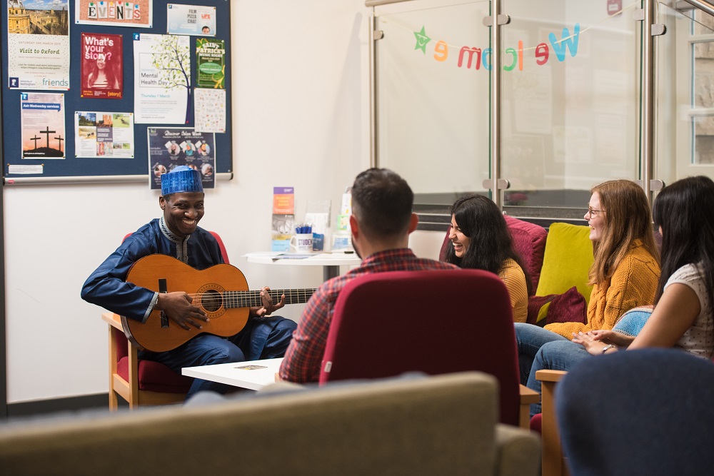 students sitting down talking and playing guitar