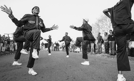 Black and white image of men dancing in South Africa street