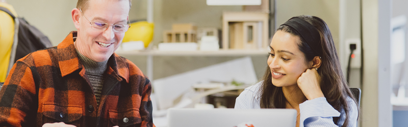 Lecturer and a student looking at a laptop and smiling