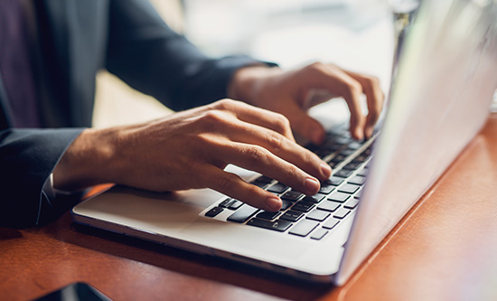 Hands typing on a laptop keyboard
