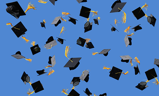 Blue sky with multiple graduation caps that have been thrown in the air