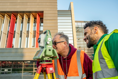 An academic and student using a terrestrial laser scanner to capture their surroundings in front of the Geospatial Building