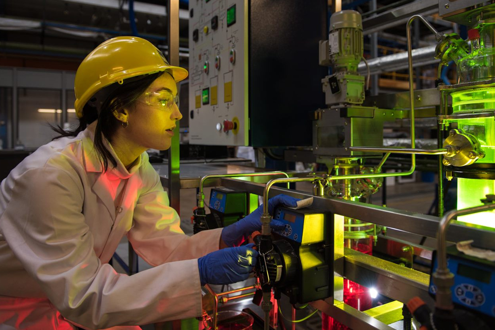 Female researcher wearing a hard hat inspecting equipment