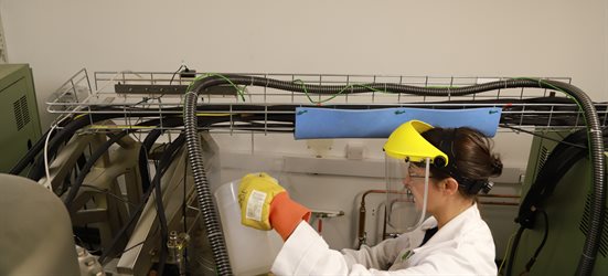A female technician working in a lab wearing PPE